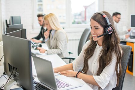 contact center staff with headset at computer and laptop