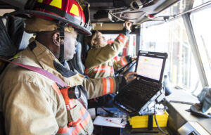 A stock photo of a female firefighter in the drivers seat of the fire engine.